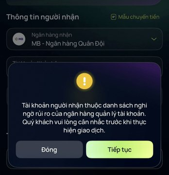 A Vietnamese banking app interface displays a warning message on a dark purple screen, stating that the recipient's account matches the bank's blocklist, with buttons to close or continue.
