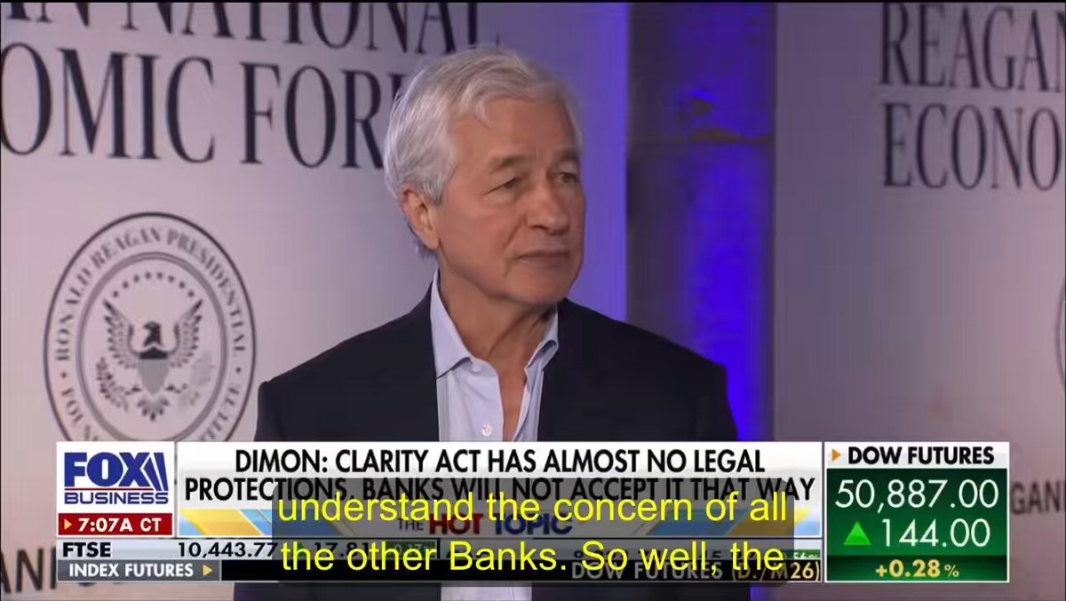 The image features a man wearing a suit, standing against a purple background with a banner that reads "FOX Business". The man appears to be talking about Bitcoin or cryptocurrency, as indicated by the text in the image. The caption below the image states that the man is representing the Holy Spirit of Bitcoin according to Jamie Dimon, who is a former US Treasury Under Secretary for Financial Institutions.