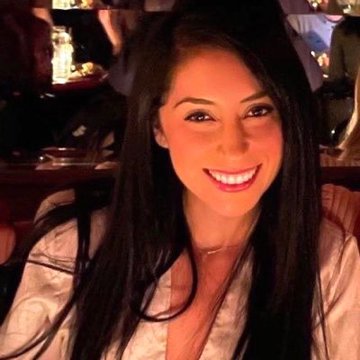 A smiling young woman with long dark hair poses for a photo in what appears to be a dimly lit venue, likely a conference or event setting. The image is associated with a post highlighting Raquel Amanda, a PR & Community Building representative at Ripple, confirming that XRP will be part of Ripple's AI-powered payments vision, particularly within the x402 framework.