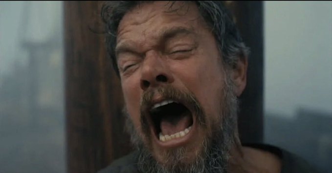 A close-up of Leonardo DiCaprio as Hugh Glass from The Revenant, screaming with his eyes closed in a snowy setting.
