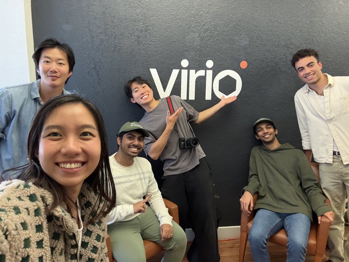 A group of six people pose together in front of a dark wall with the "virio" logo displayed behind them.