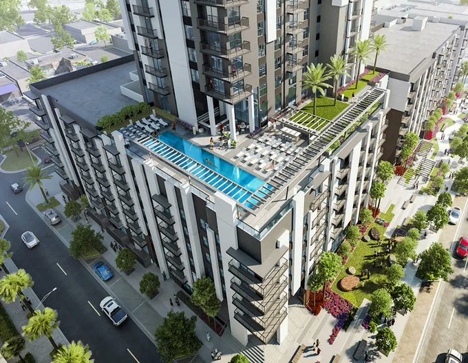 An aerial rendering showcases a modern, multi-story luxury apartment complex featuring a rooftop pool, lounge area, and landscaped terraces, representing the multi-family housing portfolio expansion referenced in Cardone Capital's strategy. The accompanying post highlights Cardone Capital's commitment to doubling down on multi-family units and BTC accumulation, contrasting with institutions pivoting to data centers.