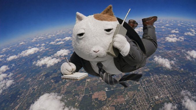A whimsical cat wearing a business suit and tie freefalls through the sky while jotting notes in a notebook and holding a brick phone, set against a backdrop of clouds and earth below—visually capturing the chaotic yet coordinated energy of $KET holders rallying around their established community.