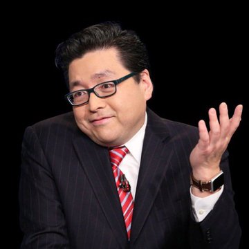 A man in a dark pinstripe suit, white shirt, and red striped tie gestures with his left hand against a black background.