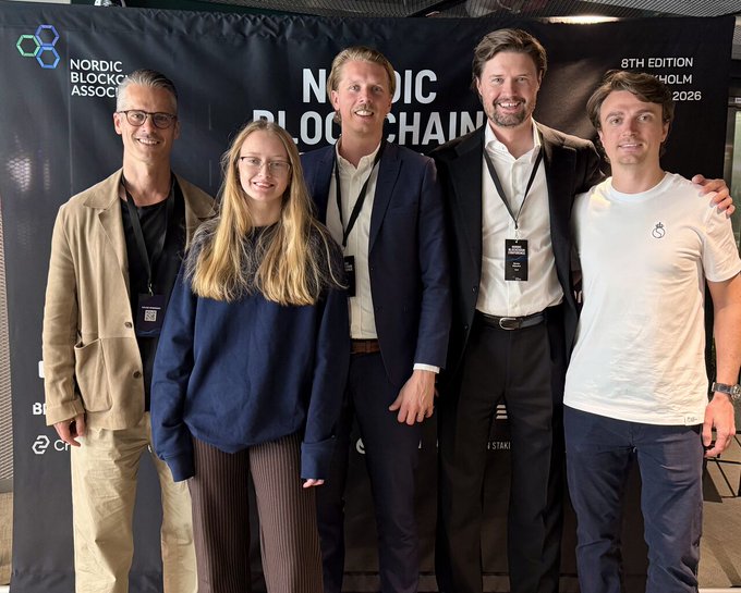 The image shows a group of five people standing together for a photo. They are all smiling and posing for the camera. The backdrop behind them features a black banner with white text that reads "Nordic Block Association" and "BybitNordic". This suggests that they might be attending an event related to blockchain technology or cryptocurrencies, possibly at the Nordic Blockchain Conference in Stockholm.