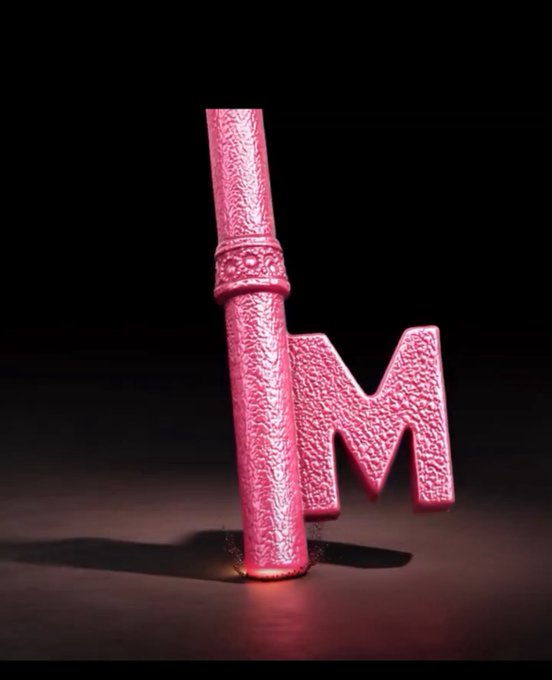 A bright pink, textured 3D sculptural piece shaped like the letters 'hm' stands against a dark background.