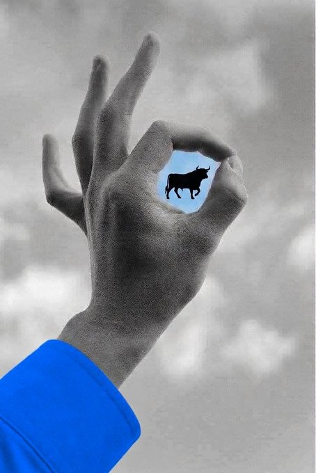 A hand forms a circle with its fingers against a cloudy sky, revealing a small silhouette of a bull within the frame. The image playfully ties to the "gm legends" post by suggesting it's not Superman but rather a bull—a symbol often associated with bullish market optimism in crypto communities.