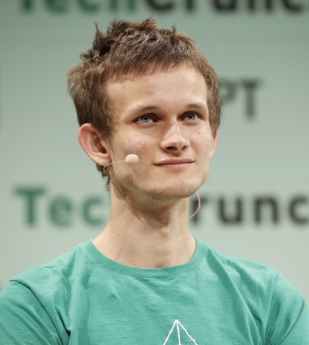 A young man with short brown hair and a slight smile wears a green t-shirt and a headset microphone, standing in front of a backdrop reading "TechCrunch," identifying him as Vitalik Buterin in the image accompanying his comments dismissing predictions of AI breaking Bitcoin's security.