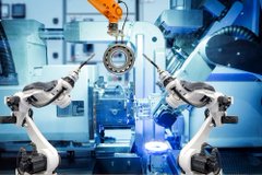 Two robotic arms equipped with sensors work together on an automotive assembly line inside a high-tech factory.