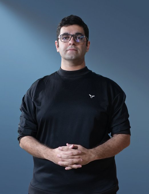 A man with dark hair and glasses, wearing a black sweatshirt with a small white logo, stands with his hands clasped against a blue gradient background—appearing to be the featured subject, likely ARafayGadit, Co-Founder of ZIGChain mentioned in the caption.