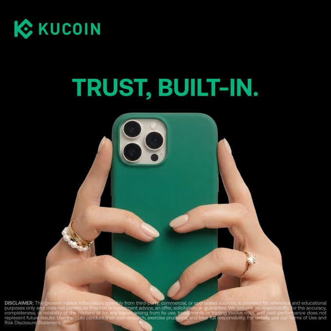 A KuCoin promotional image shows hands with manicured nails and rings forming a heart-like shape around a green smartphone, against a black background. The KUCOIN logo appears at the top, with the headline “TRUST, BUILT-IN.” and a fine-print disclaimer at the bottom, tying into the post’s message about the new KuCoin 5.0 app and the hashtag #TrustBuiltIn.