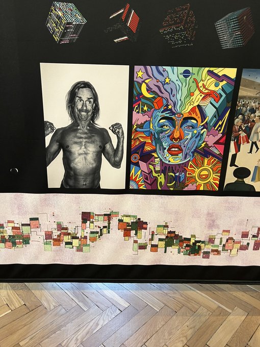 An art display features a black-and-white portrait of a shirtless man alongside a colorful pop-art portrait, with a world map made of small squares below.