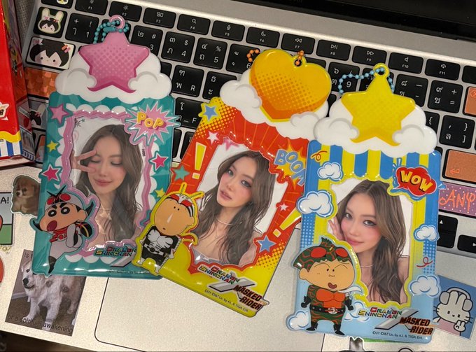Three character card holders featuring photos of a young woman are displayed on a laptop keyboard; the holders feature Crayon Shin-chan designs with 'POP,' 'BOO,' and 'WOW' text.
