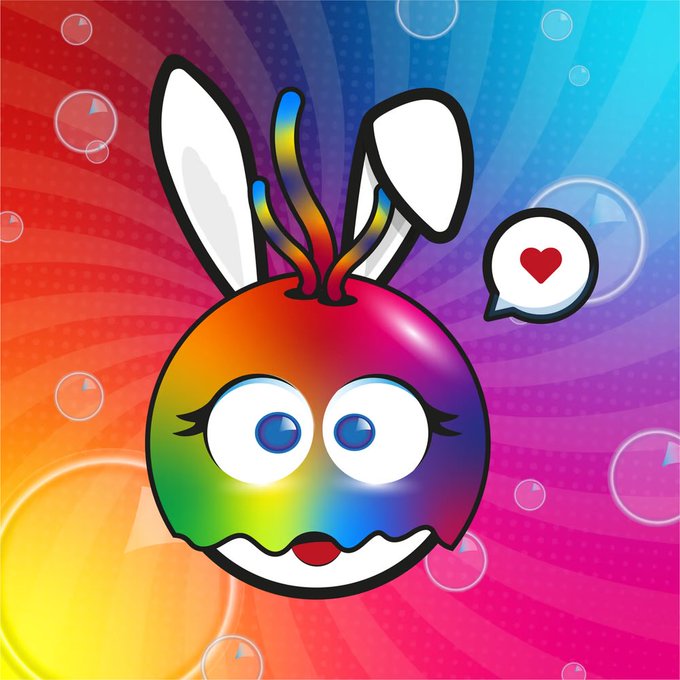 A colorful cartoon character featuring a rainbow-colored round body with bunny ears, large eyes, and a smile, with a heart speech bubble on a vibrant background.