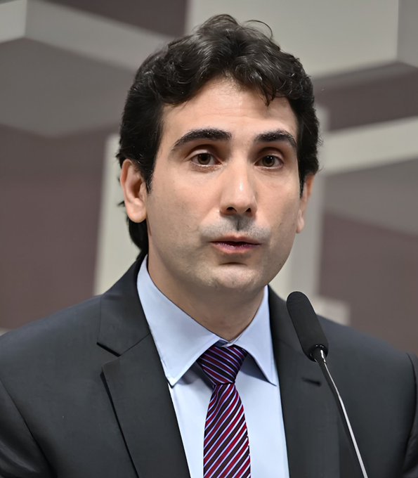 A man in a dark suit and striped tie speaks at a podium with a microphone, appearing to deliver an official statement, likely related to Brazil's Central Bank's new real-time crypto threat alert system designed to detect cyberattacks and prevent stolen funds from being laundered through exchanges.