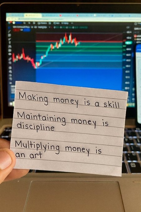 A hand holds a handwritten note in front of a laptop displaying a trading chart, reading: 'Making money is a skill, Maintaining money is discipline, Multiplying money is an art.'