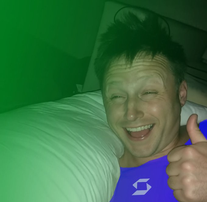A smiling man gives a thumbs-up while lying in bed, with a large green color overlay partially covering the image and a purple Dropbox logo visible in the lower portion—symbolizing a successful or uplifting "Big Week."