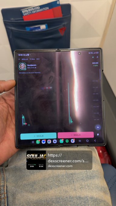 The image shows a smartphone displaying the DexScreener chart for $SOULJA on the Solana network, with the meme coin showing a massive spike in price and volume, held up in front of an airplane seat pocket while the user checks the token at 30,000 feet.
