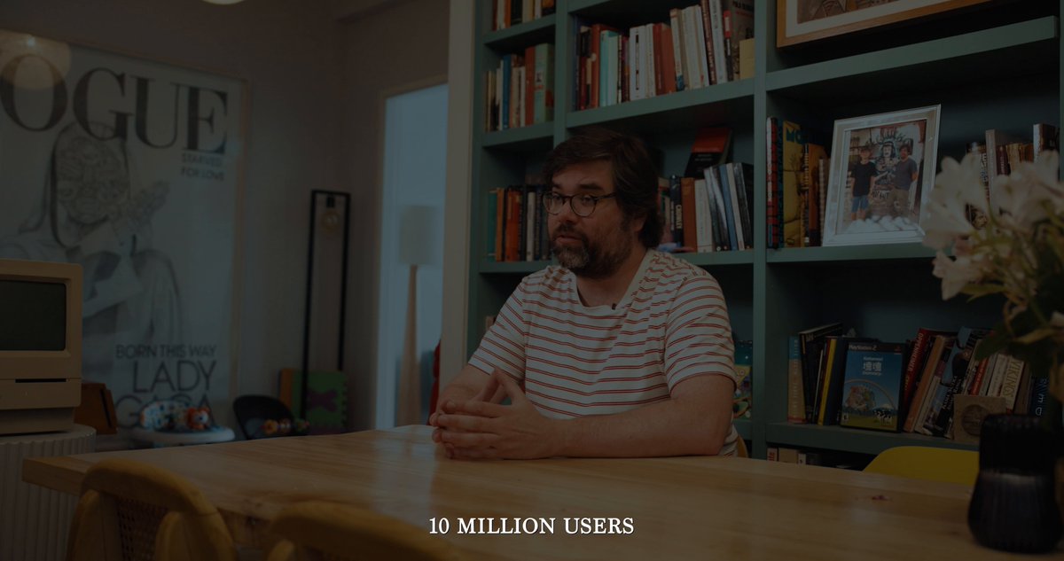 The image shows a man sitting at a table with numerous books surrounding him. The background features a wall adorned with various bookshelves filled with books, suggesting that he might be in a library or a room dedicated to reading and learning. The text "@santisiri was literally posted by the official @ethereum account months ago (see quoted tweet)" indicates that this image is part of a larger conversation about the Ethereum ecosystem and its impact on society.