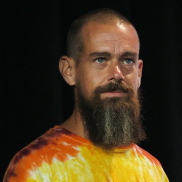 The image features a man with a long beard wearing an orange shirt, standing against a black background. The caption of the image reads "NEW- @CashApp enables $USDC transfers on #Solana #Ethereum #Polygon #Arbitrum and right now #Ripple is cooked." This suggests that the man might be involved in cryptocurrency or digital currency transactions, as indicated by the text provided.
