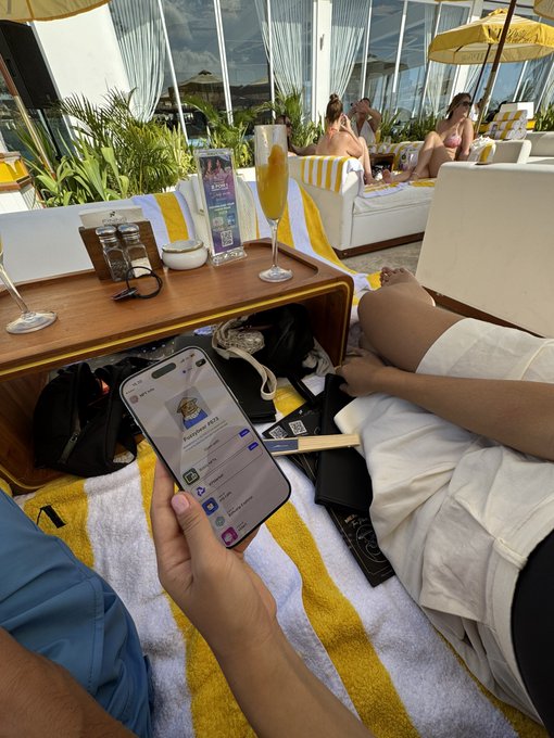 A man lounges at a beach club while scrolling his phone, which displays a "Fuzzybear" NFT transaction on what appears to be the XRP Ledger, visually capturing the real-world, on-the-spot crypto onboarding moment described in the post.