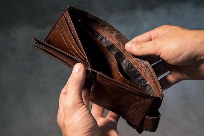 A close-up image of hands holding open a brown leather bifold wallet, revealing its card slots and empty bill compartment against a gray background.