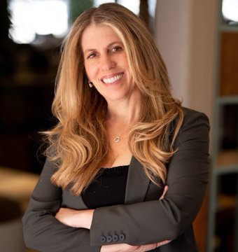In this image, a woman with long blonde hair wearing a gray blazer stands confidently against a white background. She has her arms crossed over her chest and is smiling at the camera. The caption below the photo reads "$XLM : Denelle Dixon, CEO & Executive Director of the Stellar Development Foundation : The DTCC is the backbone of global capital markets, and integrating their tokenization service with Stellar connects public blockchain networks to regulated market infrastructure."