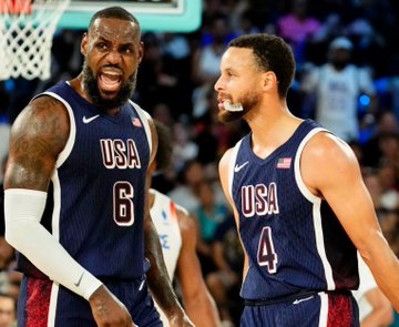 Two USA Basketball players, LeBron James (#6) and Stephen Curry (#4), share a celebratory moment in their national team jerseys, with the image highlighting the two stars whose potential pairing has driven Golden State's status as favorites on Polymarket to sign LeBron James.