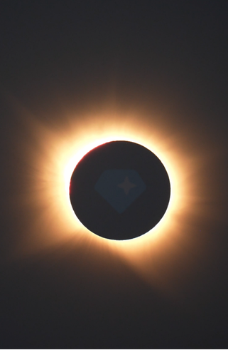 A total solar eclipse with the Moon silhouetted against the Sun's glowing corona, overlaid with the Hedera (HBAR) logo at the center. The image visually ties to the caption "GRAMazing eclipse" by playfully referencing a "Grammy"-level awe, with the HBAR emblem suggesting a crypto community celebration of the celestial event.