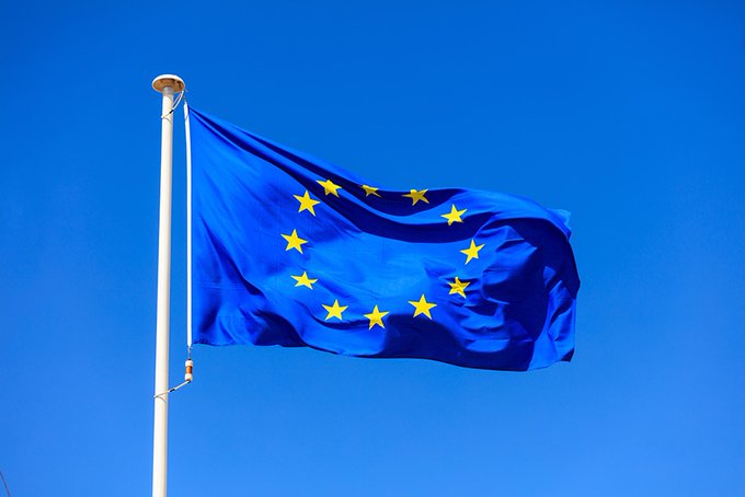 The European Union flag waves against a clear blue sky, symbolizing the EU's unified stance as it announces its 21st sanctions package against Russia, targeting Russian financial institutions, crypto platforms, and oil traders.