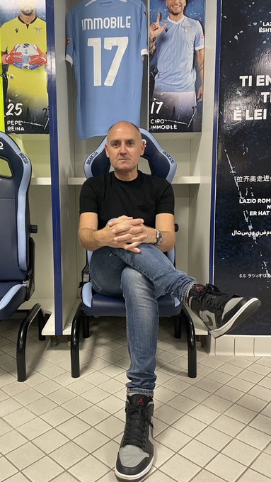 The image features a man sitting in a locker room, wearing black clothing and grey shoes. The man appears to be posing for a photo or taking a break from his soccer activities. In the background of the image, there are posters advertising the World Cup, which suggests that this is likely a sports facility related to the event. The post also mentions that the 24-hour countdown to the World Cup has kicked off and that the players are ready to engage with fans.