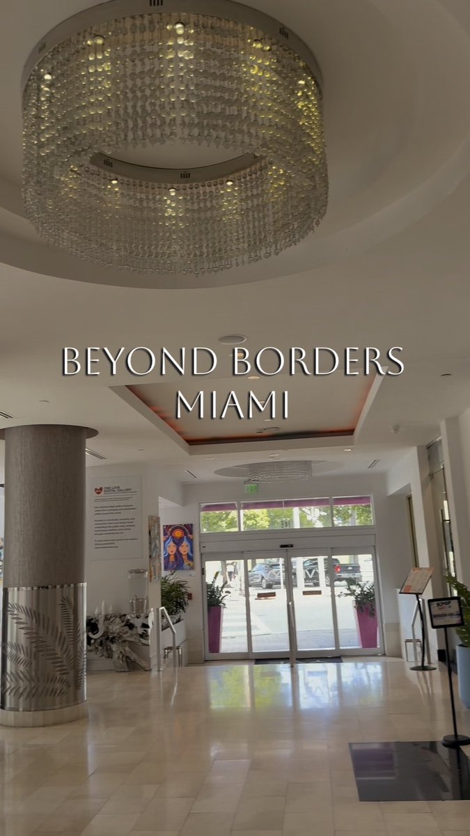 An Instagram story or post showing the elegant entrance lobby of the 'Beyond Borders Miami' venue, featuring a large circular chandelier and glass doors.