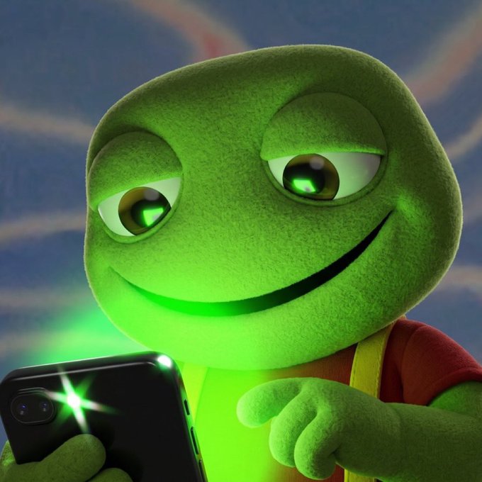A 3D render of a cute green frog-like character with a sinister smile, wearing a red shirt and yellow straps, looking at a smartphone that emits green light.