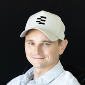 A man wearing a light-colored cap with a dark "E" logo smiles in a close-up portrait. The image accompanies a post about participating in an Ethos presale at sale.ethos.network/3P7D57N, suggesting he is the founder or a representative of the Ethos project.