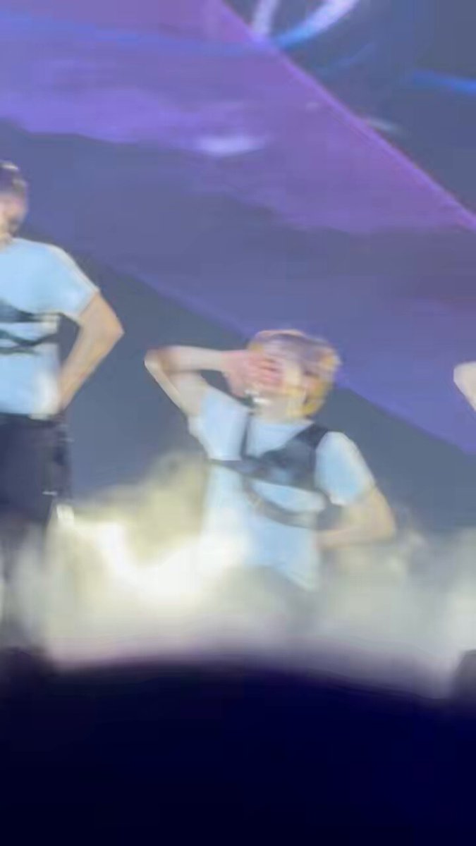 The image shows a person wearing a white shirt with black straps, standing next to another person who has their hand up to their face as if they are about to sneeze or make a funny face for the camera. The background of the photo is dark purple and features smoke coming from behind them. There is also text in the image that reads "Oh my god, I just realized my baby dog can be sexy.. Is the Sanghyeon Chains ending insane?".