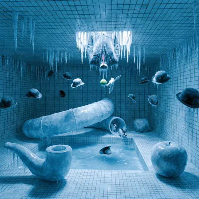 A surreal blue-tiled room featuring ice-formed sculptures including a pipe, apple, tube with wolves, floating bowler hats, and a face emerging upside-down from the ceiling with icicles.