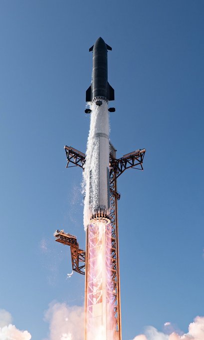 A SpaceX Starship rocket lifts off from its launch tower against a clear blue sky, flames and vapor trailing beneath it. The powerful ascent visually embodies the post's message about humanity's journey to reach the Moon and Mars within our lifetime.