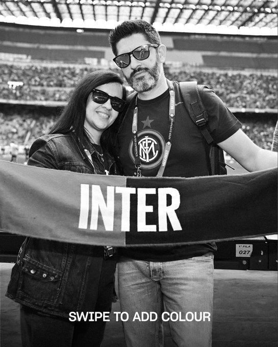 A smiling couple poses in black and white at a stadium, holding an "INTER" banner while wearing an official FC Internazionale Milano jersey, with the caption "SWIPE TO ADD COLOUR" inviting viewers to engage with the Inter Milan fan experience featured in the accompanying post.