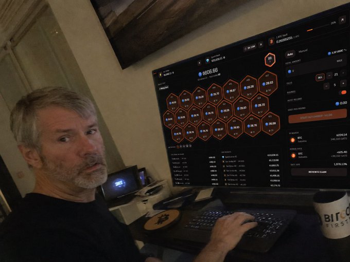 A man sits at a desk looking at a monitor displaying what appears to be a BTC mining interface with hexagonal stats showing $8606.66, alongside a Bitcoin-branded mug and keyboard, illustrating the post about mining BTC on Solana with $24,116.78 in the Epoch Vault and a $7,054.15 Sat Strike armed.