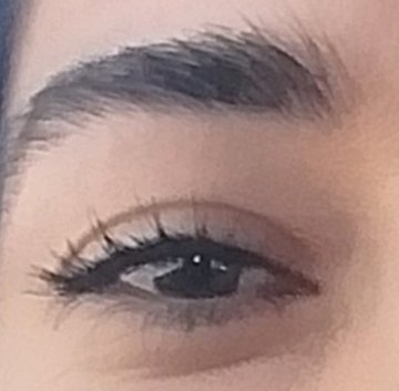 A close-up photograph of a person's eye with dark eyeliner, mascara, and well-groomed eyebrows.