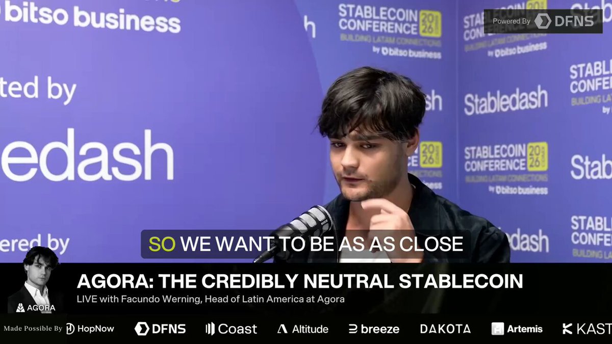 The image features an interview with a man wearing a black shirt, sitting behind a microphone at a conference. He appears to be speaking into the microphone, possibly about the current state of the stablecoin market or some other topic related to cryptocurrency. The text on the image states that he wants to be as close to the metal as possible and that they filed for a national trust bank charter with the OCC.