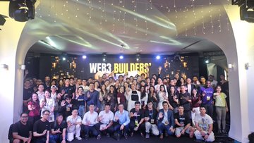 The image features a large group of people posing for a photo at an event called the Web3 Builders' Summit, which took place in 2016. The attendees are gathered under a stage with lights, creating a festive atmosphere. The backdrop includes banners that read "WEB3 BUILDERS" and "#RWAs", indicating the theme of the summit. The group consists of both men and women, all dressed up for the occasion. They are standing close to each other in front of a large screen displaying the event's name on it.