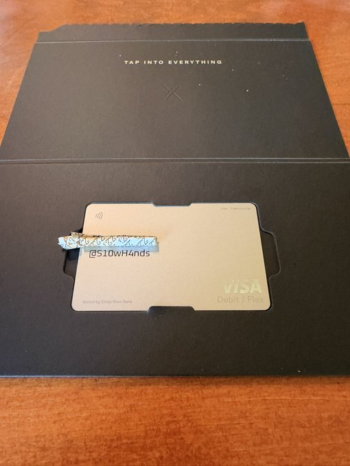 A promotional image showing a Visa Debit/Flex card placed on a black box with the text 'TAP INTO EVERYTHING' and an 'X' logo, with the card partially obscured by a blue bar containing the text '@510wH4nds'.