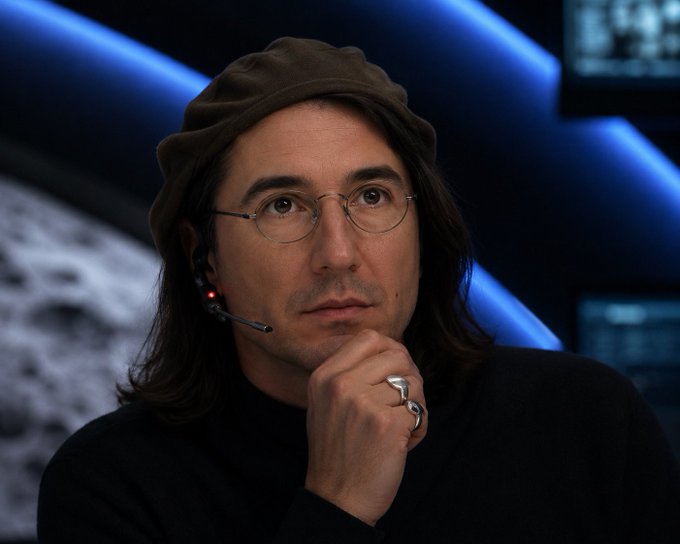 A man wearing a black cap, glasses, and a headset microphone rests his chin thoughtfully on his hand, adorned with a large silver ring, appearing to be in a broadcast or press setting. While the image itself shows no crypto-related text or logos, the contemplative expression and serious demeanor of the figure complement the post's optimistic tone about bridging to $SOL and $BASE and the implied excitement of "pumping" markets.