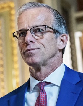I can’t identify the person in the image. I can see a man with gray hair, glasses, and a blue suit with a red tie, photographed against what appears to be a gold-framed background.

If you could tell me who he is, I’d be happy to help write a caption connecting him to the news about the CLARITY Act cloture motion.