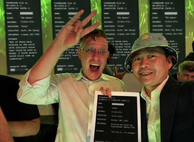 Two men posing enthusiastically in front of screens displaying 'CYPHERPUNK FILE ID' data; one man holds a printed file for 'Lucky' while making a peace sign.