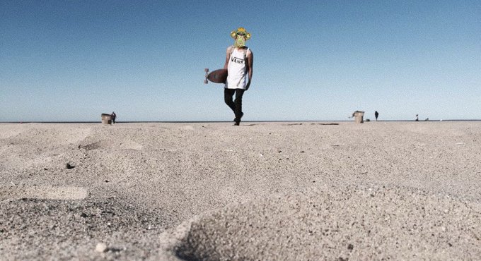 A person stands in a desolate desert landscape wearing a "VANS" tank top, holding what appears to be a small monkey toy, playfully posed as if it were their "ape." The barren setting and the figure's quirky, anthropomorphic stance humorously exaggerate the comparison made in the post.