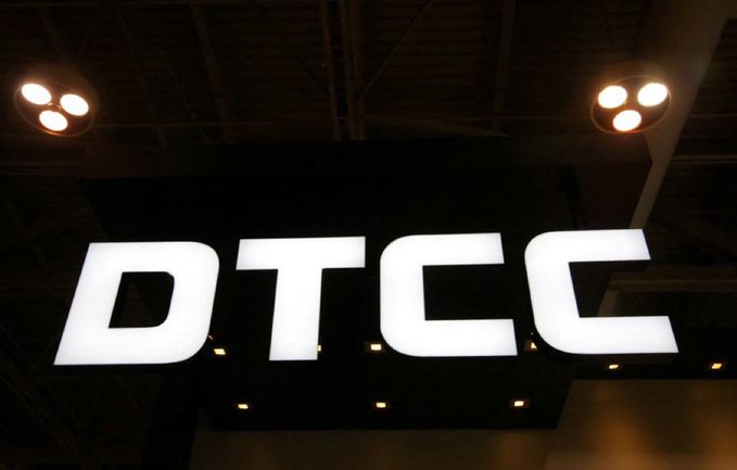 An illuminated white sign reading 'DTCC' is suspended from a dark ceiling with visible spotlights in what appears to be an indoor venue or convention space.
