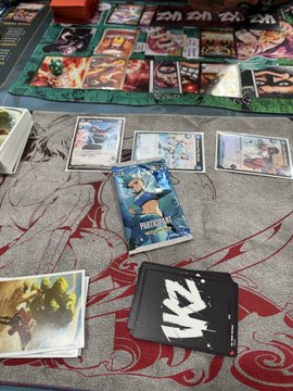 The image shows an Azuki TCG playmat with cards and a "Participation Pack." It visually represents the user's participation in the Azuki TCG starter deck event mentioned in the caption.