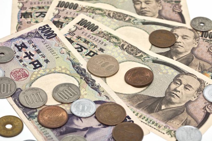 A collection of Japanese yen, including 10,000 yen, 5,000 yen, and 1,000 yen banknotes, along with various coins, arranged on a flat surface.